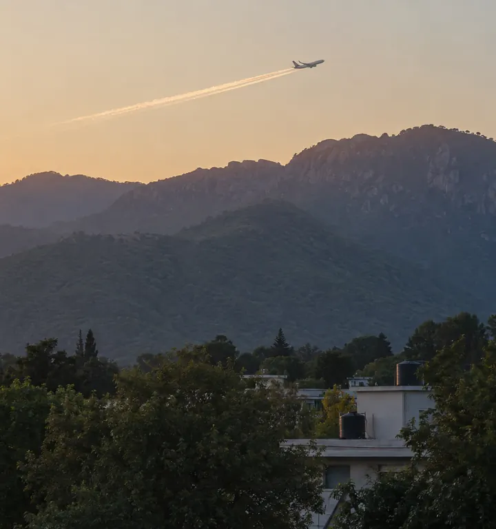 A passenger jet climbing over the Margalla Hills at last light